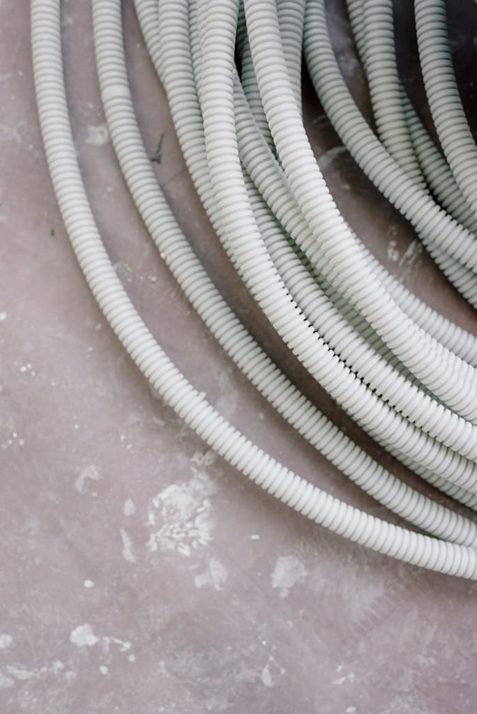 pexels-photo-5691657 Close-up of coiled white electrical wire on a rough, textured concrete surface.