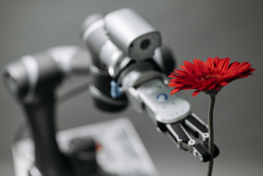 pexels-photo-8438966 A robotic arm delicately holds a vibrant red flower, symbolizing technology's harmony with nature.